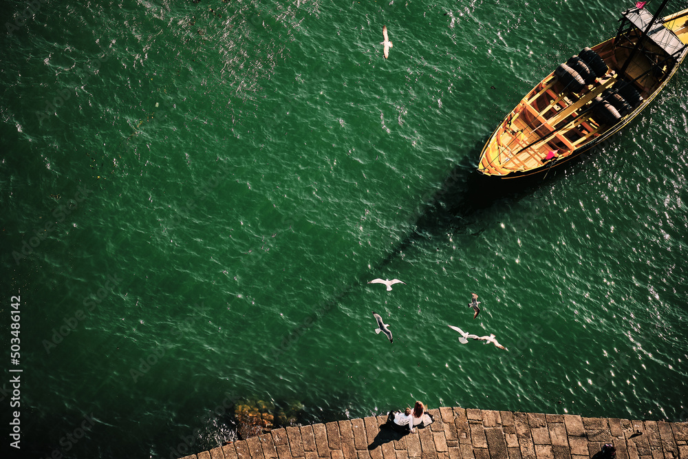 Top view of a couple in front of the river Duoro Oporto Portugal with a boat at sunset and seagulls flying overhead