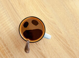 Coffee cup with funny screaming in fear face, top view. Pareidolia effect at breakfast