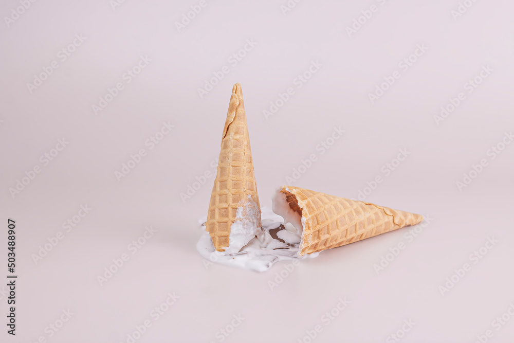 Melting ice cream with broken empty waffle cones on pastel color backgrounds. Summer creative food concept. Melting ice cream with broken empty waffle cones on pastel color backgrounds. Summer creative food concept.