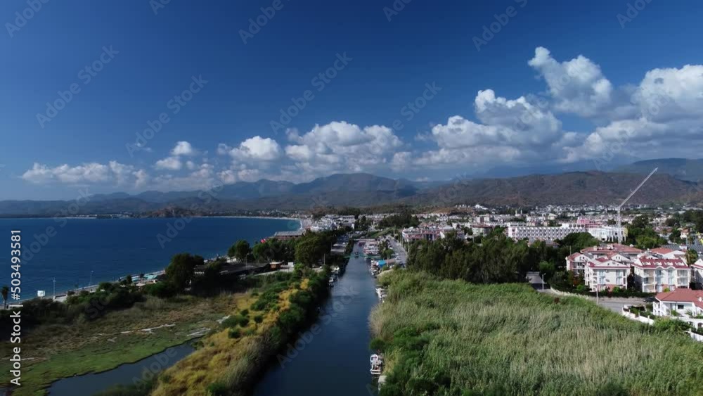 Landscape of Turkish lands with river lying along the shoreline and city located next to it. Aerial view of the Fethiye and Mediterranean sea at warm summer day. Concept of popular travel destination. Landscape of Turkish lands with river lying along the shoreline and city located next to it. Aerial view of the Fethiye and Mediterranean sea at warm summer day. Concept of popular travel destination.