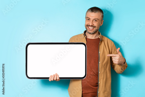 Joyful Man Holding Big Mobile Phone Showing Screen, Blue Background