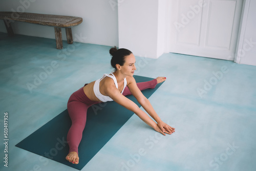 Caucasian girl practicing yoga at spacious home