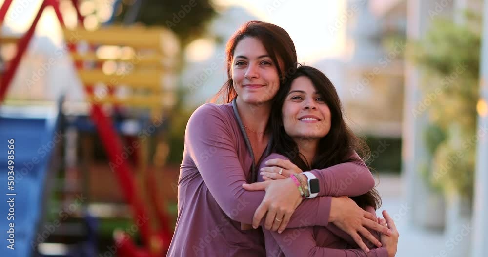 Two adult happy sisters posing together outside twin siblings with same clothes Two adult happy sisters posing together outside twin siblings with same clothes