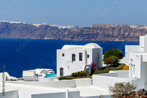 Traditional greek white houses on Santorini coast near the Aegean Sea. Village on the cliff under blue sky.