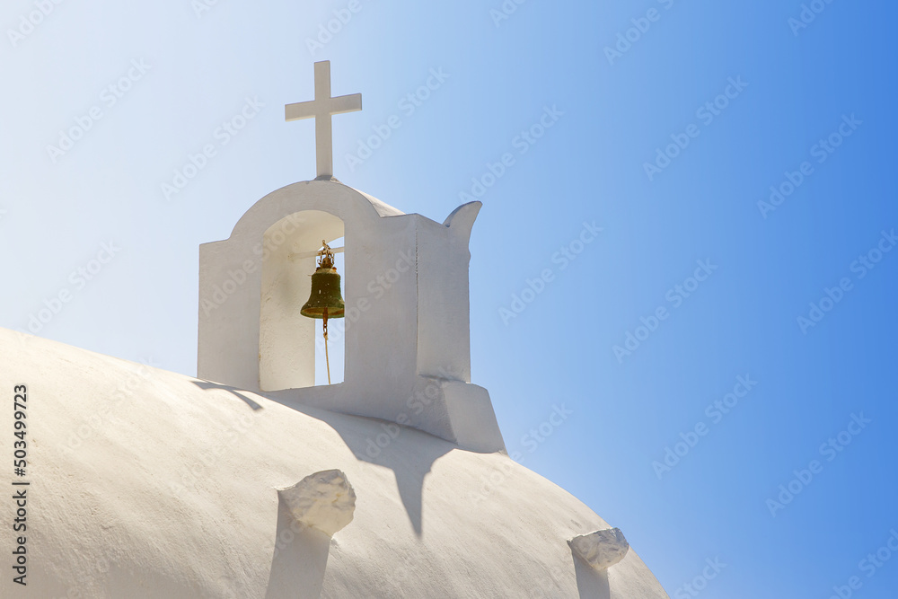 White Orthodox Church belfry with cross and bell on sky background. Santorini island, Greece. White Orthodox Church belfry with cross and bell on sky background. Santorini island, Greece.