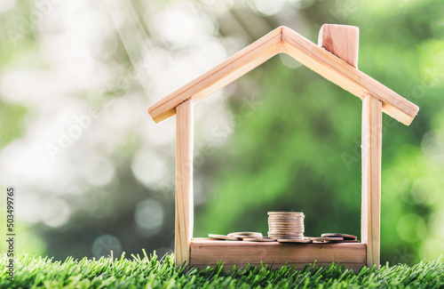 Coin is placed in a model wooden house. concept the growth of finance. planning savings money of coins to buy a home concept for property, mortgage and real estate investment, savings for a house.