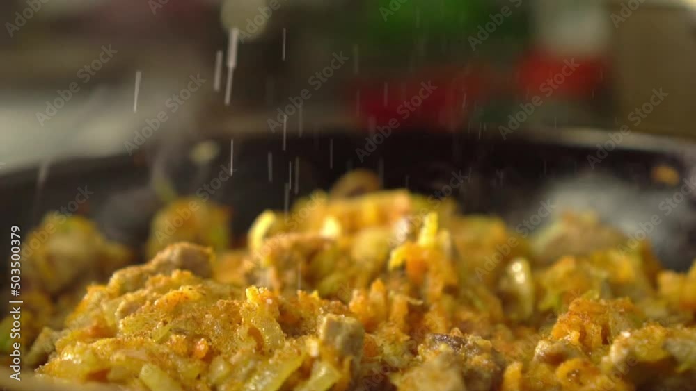 Frying pan with meat and vegetables close-up. Preparation of gravy, goulash or sauce. Vegetarian food. Chinese cuisine or traditions. Sakshuka. Woman's hand adds salt or pepper to spices. Frying pan with meat and vegetables close-up. Preparation of gravy, goulash or sauce. Vegetarian food. Chinese cuisine or traditions. Sakshuka. Woman's hand adds salt or pepper to spices.