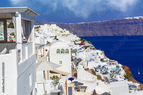 Traditional greek white houses on Santorini coast near the Aegean Sea. Village on the cliff under blue sky.