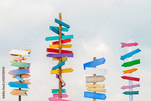 Colorful wooden direction arrow signs on wooden poles photo