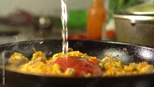 Frying pan with meat and vegetables close-up. Preparation of gravy, goulash or sauce. Vegetarian food. Chinese cuisine or traditions. Sakshuka. cook adds or pours water and there is steam. photo