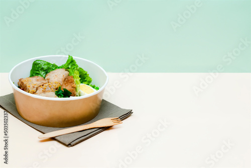 Healthy food lunch in kraft paper carton eco friendly box disposable bowl packaging container on green background. chicken, eggs, greens dinner. Take away delivery. environment protection, copy space.