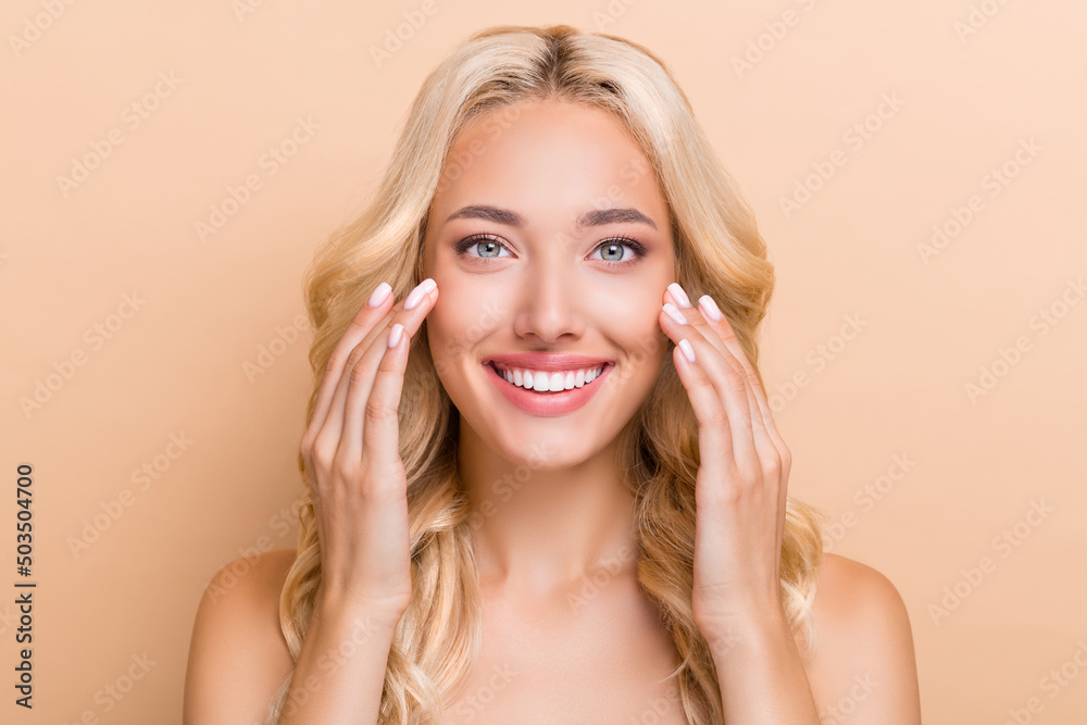 Obraz premium Portrait of attractive cheerful wavy-haired girl washing clear pure skin uplift effect isolated over beige pastel color background