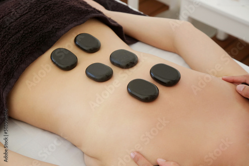 Young woman getting hot stone massage in spa salon