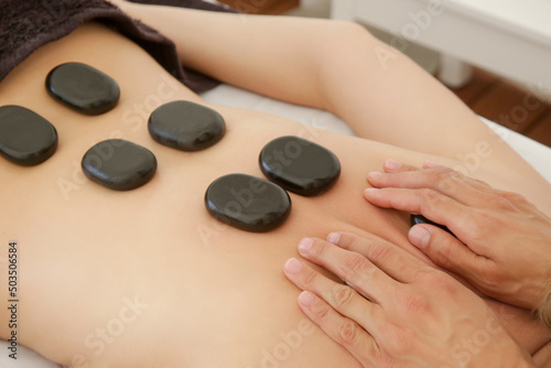 Young woman getting hot stone massage in spa salon