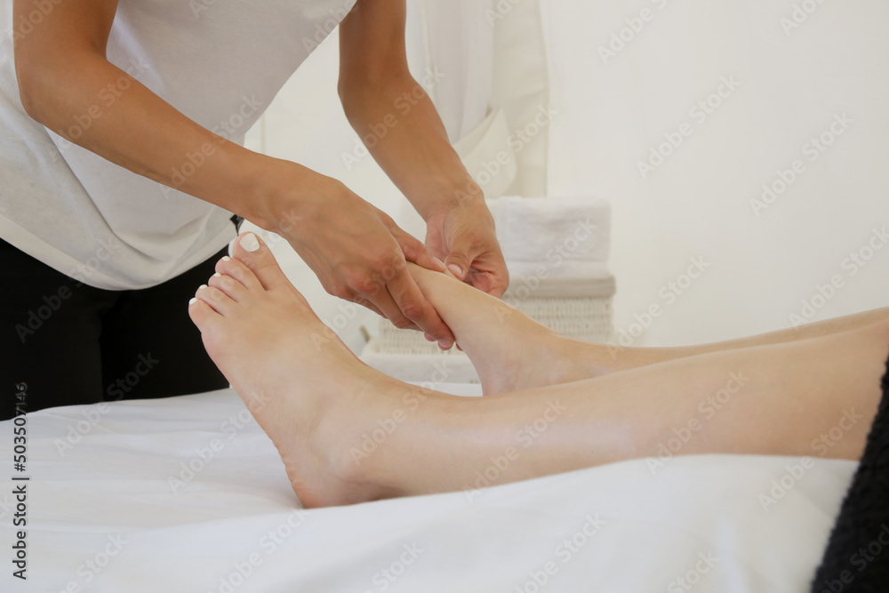 Fototapeta premium Young woman having feet massage in beauty salon