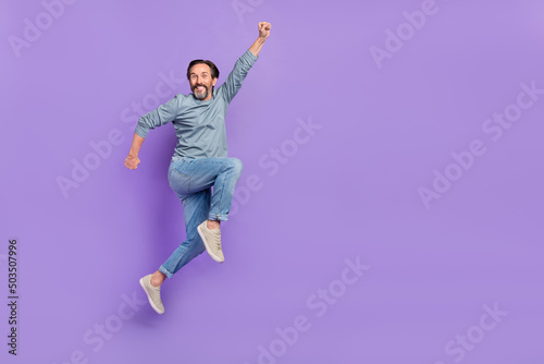 Full body profile side photo of cheerful mature man superhero jump isolated over purple color background