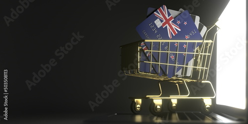 Shopping cart full of credit cards mockups with flags of New Zealand on the laptop. 3D rendering