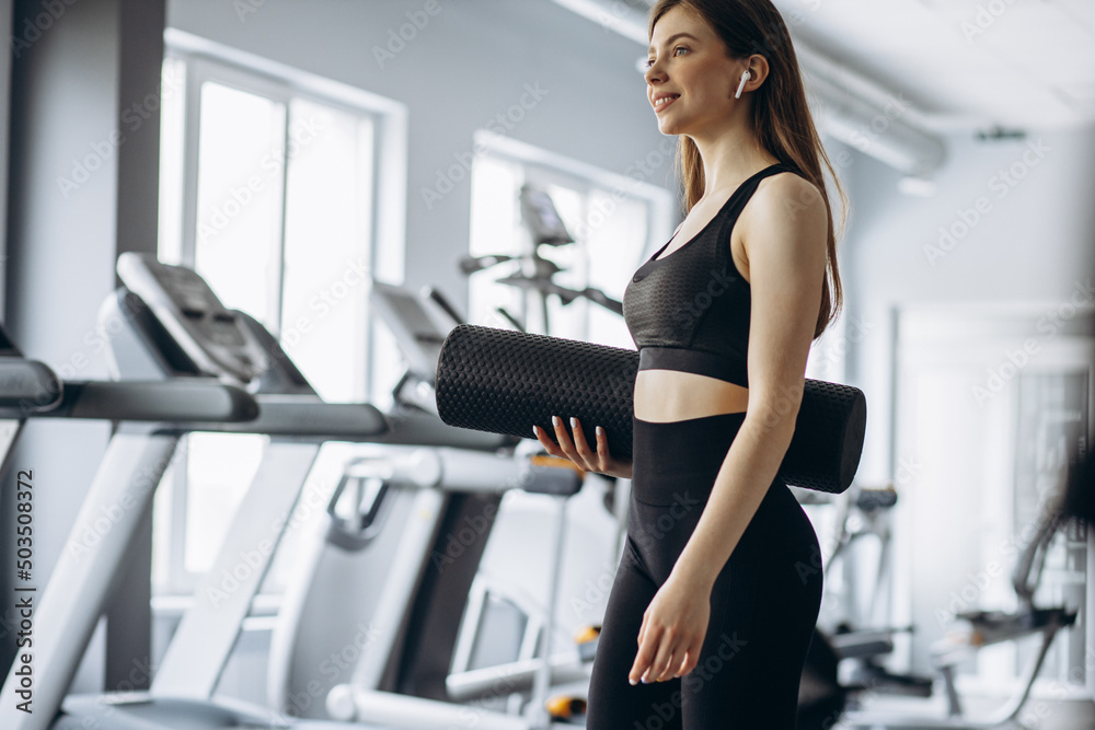 Fototapeta premium Woman in earphones listening to music at the gym