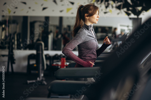 Sporty woman running on treadmill at the gym