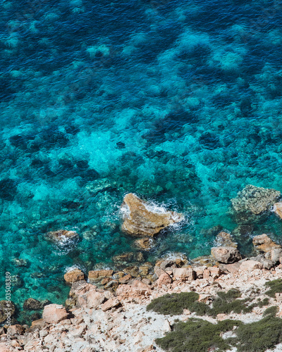 Vertical high angle shot of the vibrant clear blue waters at the Atlantis cove in Ibiza photo