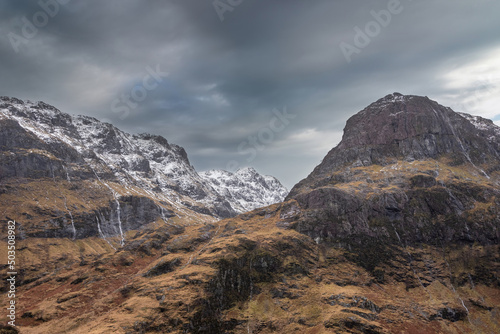 Majestic Winter landscape image of snowcapped Three Sisters mountain range in Glencoe Scottish Highands with dramatic sky