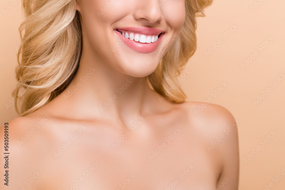 Cropped view portrait of attractive cheerful wavy-haired woman perfect implant teeth isolated over beige pastel color background Cropped view portrait of attractive cheerful wavy-haired woman perfect implant teeth isolated over beige pastel color background