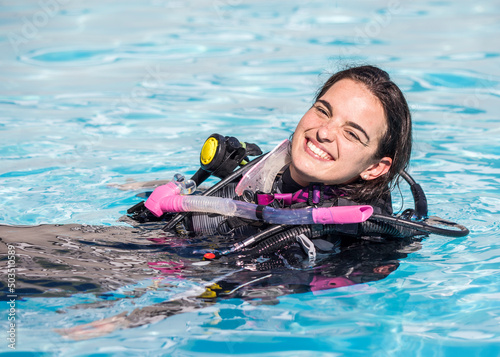 Young woman with scuba gear on in a pool smiling at the camera