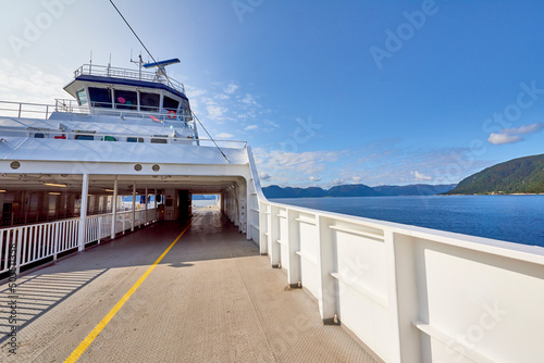 Empty deck of a ferry in the Norwegian Sea, in the background the coast of a Norwegian fjord on a sunny day. © trattieritratti