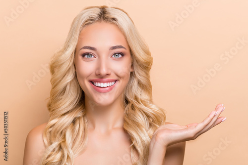 Portrait of attractive cheerful wavy-haired girl holding on palm ad copy space exfoliation isolated over beige pastel color background