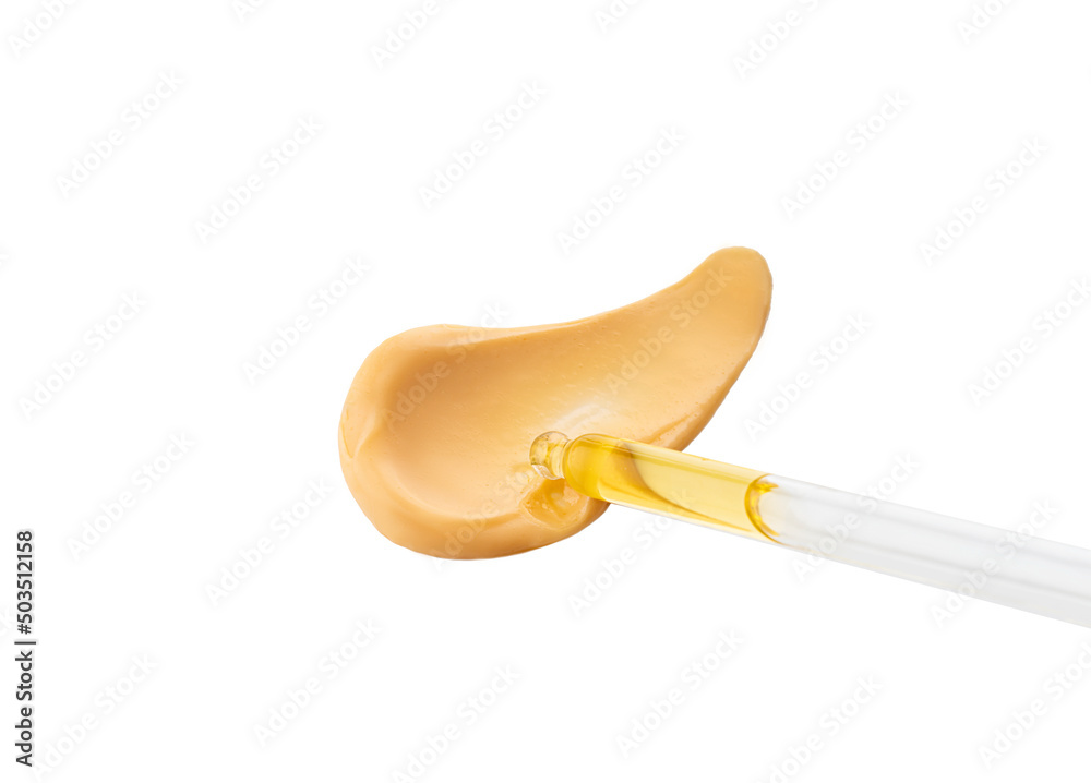 Cosmetic pipette with drops of oil or serum, on the background of orange cosmetic cream smear. Close-up, selective focus Cosmetic pipette with drops of oil or serum, on the background of orange cosmetic cream smear. Close-up, selective focus
