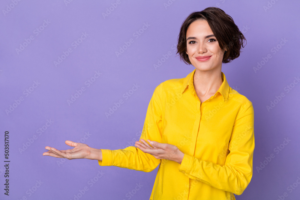 Photo of nice young lady indicate empty space wear yellow shirt isolated on violet color background Photo of nice young lady indicate empty space wear yellow shirt isolated on violet color background