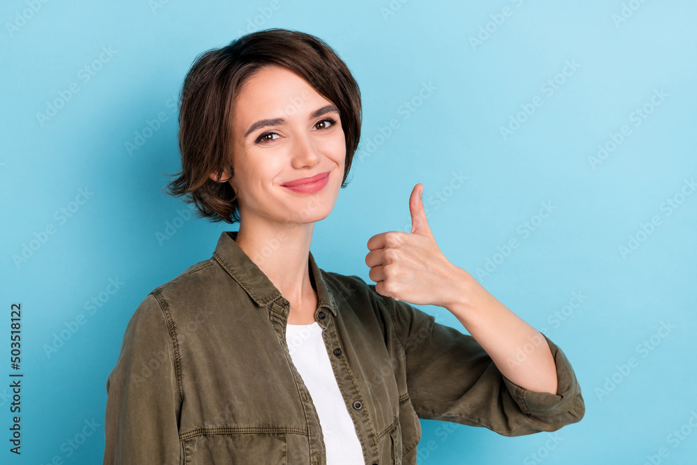Photo of cool young brunette business woman thumb up wear khaki shirt isolated on blue color background Photo of cool young brunette business woman thumb up wear khaki shirt isolated on blue color background