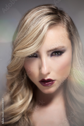 Close up of Sexy Blond Smokey Eyes Fashion Model Posing with Perfect Long Hair Looking at Camera in Studio with Bokeh