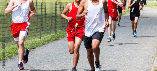 High school boys running in a cross country race on a gravel path