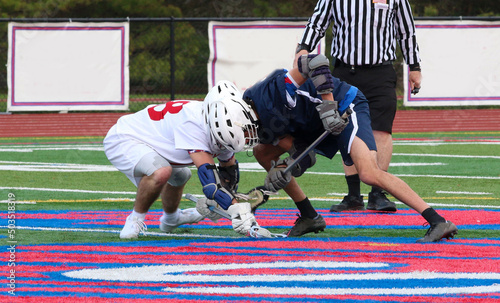 Fighthing for the ball during a face off in a lacross game photo