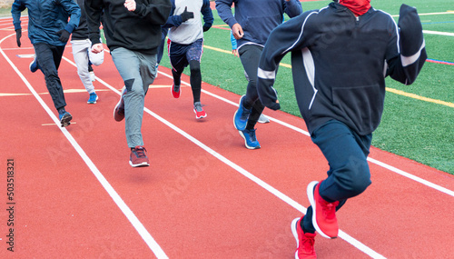 Group of boys running on a track on a cold day