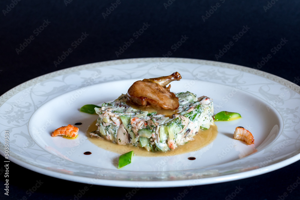 Olivier salad with quail on white plate on dark table Olivier salad with quail on white plate on dark table