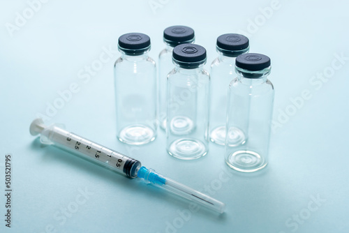 syringe and medical glass bottles on blue background