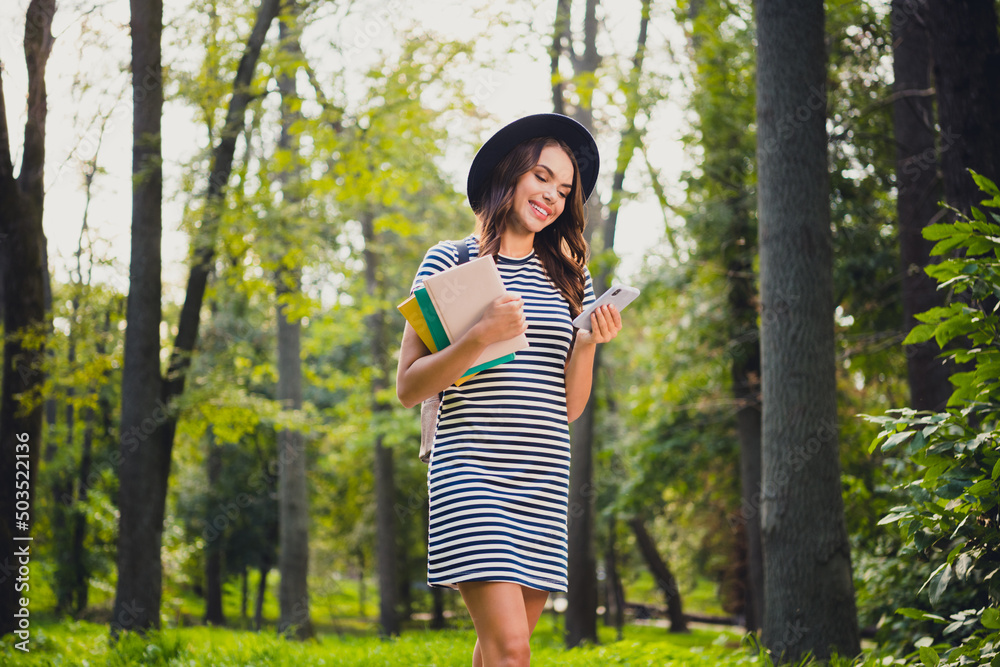Portrait of beautiful cheerful schoolgirl holding book using device writing smm post pastime on fresh air outdoors Portrait of beautiful cheerful schoolgirl holding book using device writing smm post pastime on fresh air outdoors