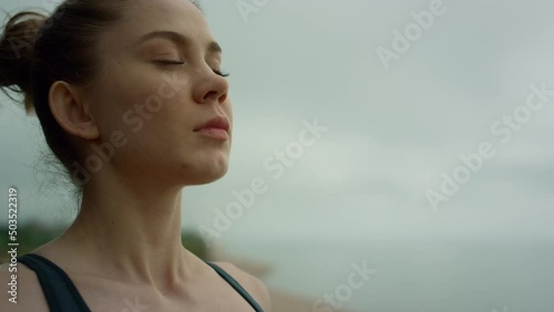 Yogi woman making deep breath meditating on beach. Lady practicing yoga close up photo
