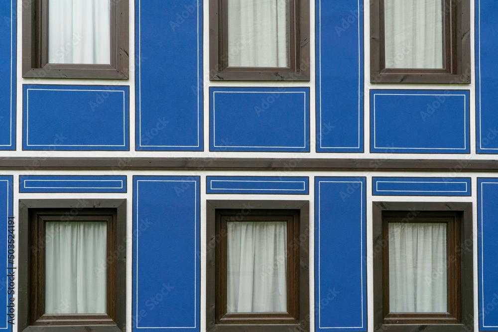 part of the facade of a building painted blue with wooden windows and a door
