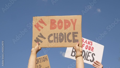 Protesters holding signs My Body My Choice, Abortion Is Healthcare and Bans Off Our Bodies. People with placards supporting abortion rights at protest rally demonstration.