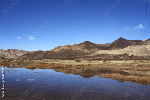 andscape between Tibet to Shigatse  Tibet China.The rock mountains range  dried grasses reflection in the lake with blue sky