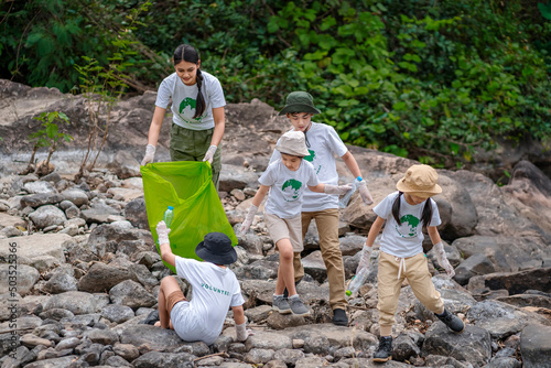 Volunteer Asian and children are collecting plastic bottles that flow through the stream into garbage bags to reduce global warming and environmental pollution. Volunteering and recycling concept.