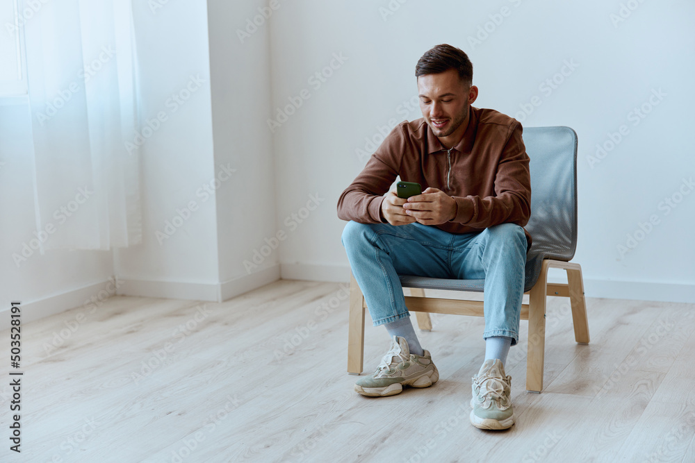 Enjoyed relaxing game in phone happy young man gamer sitting at chair in office on over white wall home background. Mobile RPG game concept. Copy space for ad. Mobile App offer Banner Mockup Enjoyed relaxing game in phone happy young man gamer sitting at chair in office on over white wall home background. Mobile RPG game concept. Copy space for ad. Mobile App offer Banner Mockup
