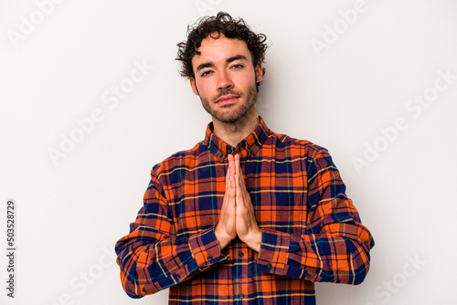 Obraz na plátně Young caucasian man isolated on white background praying, showing devotion, religious person looking for divine inspiration
