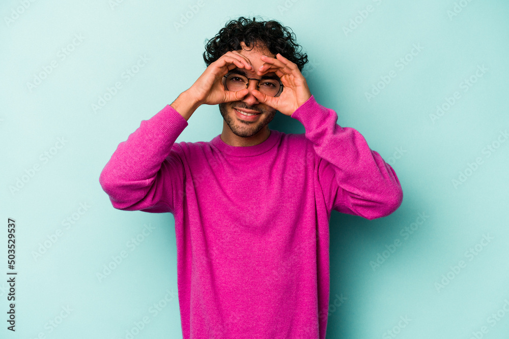 Young caucasian man isolated on white background showing okay sign over eyes