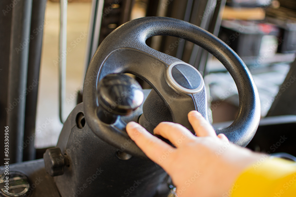 Hand rotates the steering wheel of the electric forklift, right, left. Turn and steer the driving machinery. Hand rotates the steering wheel of the electric forklift, right, left. Turn and steer the driving machinery.