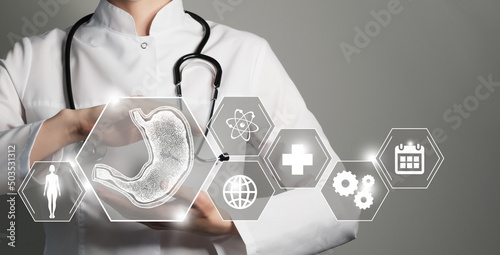 Unrecognizable female doctor holding graphic virtual visualization model of Stomach organ in hands. Multiple medical icons on the background. photo