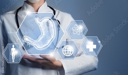 Unrecognizable female doctor holding graphic virtual visualization model of Stomach organ in hands. Multiple medical icons on the background. photo